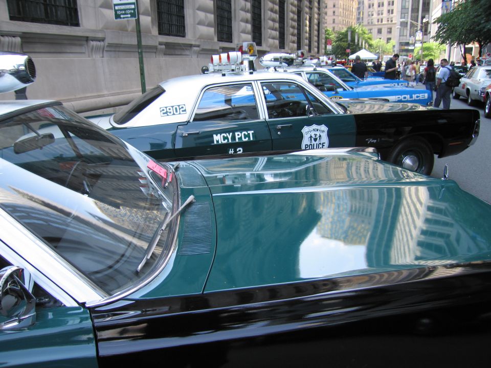 Roofline of a green-and-white NYPD police car reflecting nearby buildings