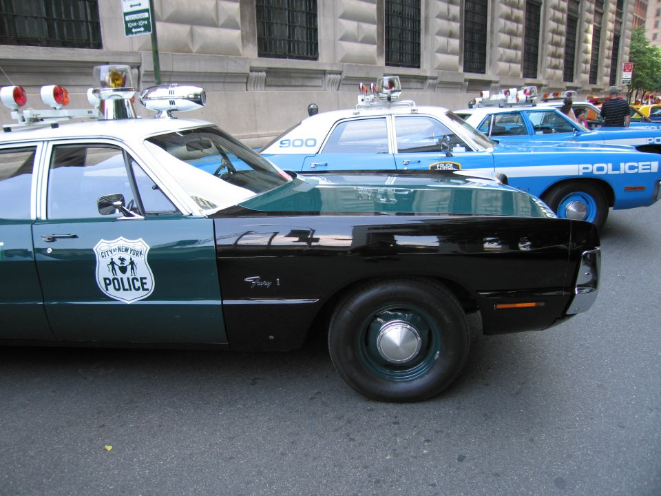 Front of a green-and-white NYPD cruiser with a blue police car behind it