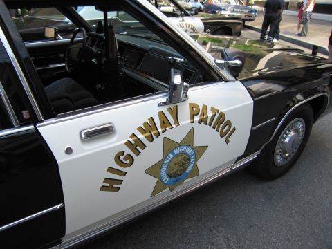 1991 Ford LTD Crown Victoria - Close-up of a black-and-white police car door lettered Highway Patrol with the California Highway Patrol gold star emblem.