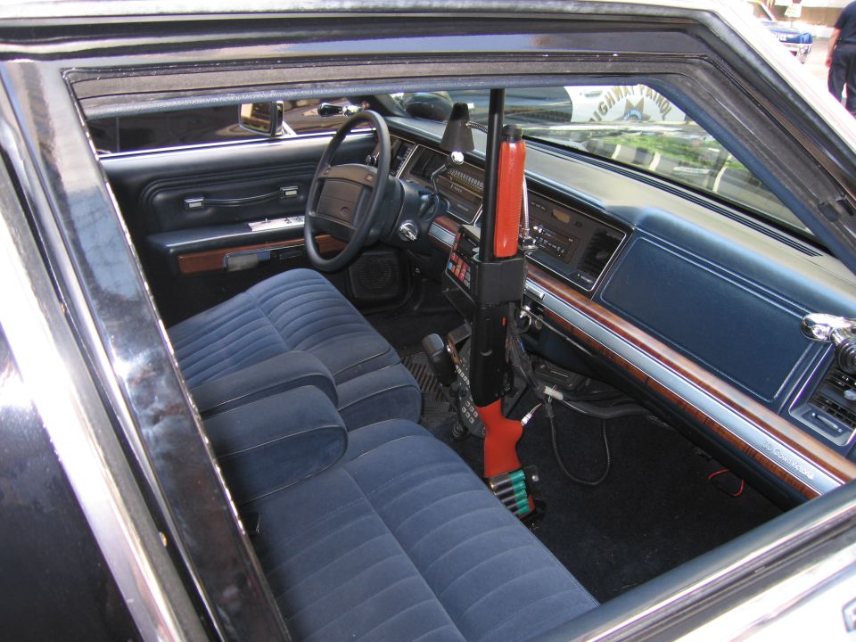 Police car interior with blue cloth bench seat and a red shotgun mount