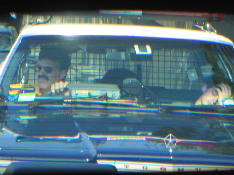 Mustached driver in sunglasses behind the windshield of a police car