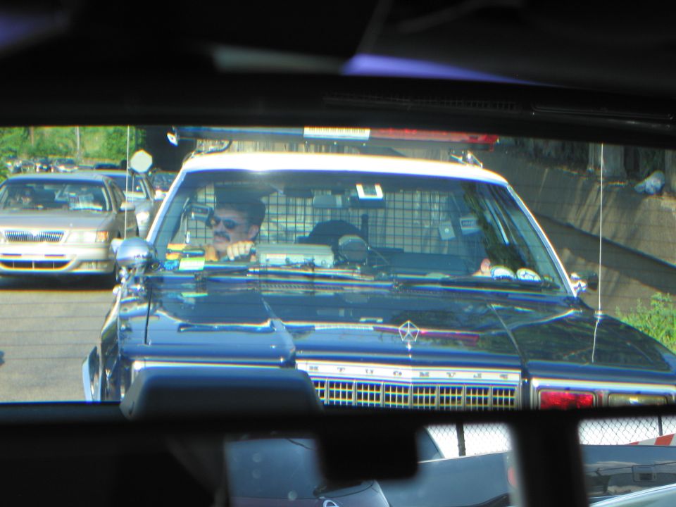 Police car with driver seen through a rear window in slow traffic