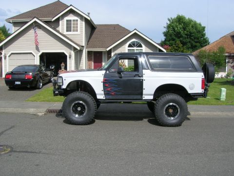 1996 Ford Bronco - A lifted Ford Bronco with custom paint sits parked on a suburban street.