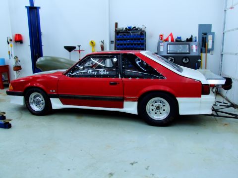 1990 Ford Mustang - Side profile of a red and white 1990 Ford Mustang drag car, a prominent '5.0' badge and racing slicks.