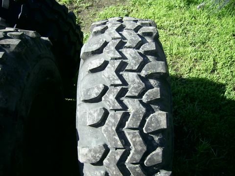 1978 Ford Bronco - A close-up of a tire's tread pattern is shown against a grassy background.