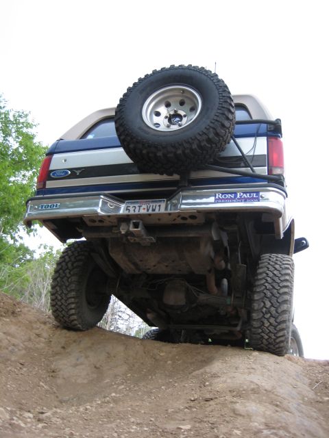 1996 Ford Bronco - This 1996 Ford Bronco is captured from a low rear angle as it navigates an off-road trail, its spare tire and distinctive body style.
