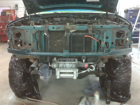 1996 Ford Bronco - Front view of a green Ford Bronco with its hood open, revealing the engine and a winch mounted on the bumper.