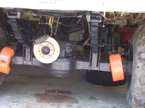 1987 Suzuki Samurai - The underside of a vehicle is shown, supported by orange blocks.