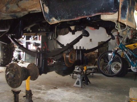 1987 Suzuki Samurai - The underside of a vehicle is shown with its suspension components exposed, with a bicycle in the background.
