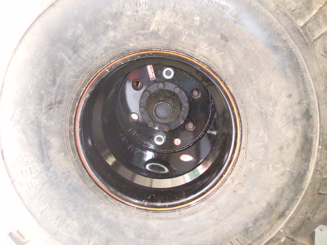 Close-up of a black wheel with a tire and lug nuts