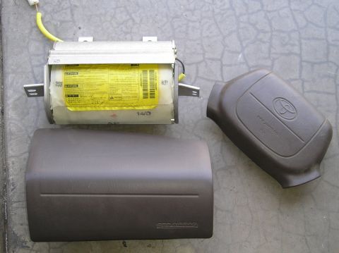 1986 Toyota Hilux - Disassembled Toyota airbag system components including the module, steering wheel cover, and dash trim.