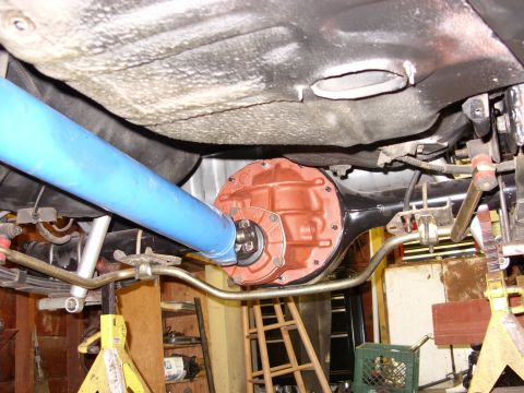 1978 Ford Mustang II - Underside view of a rear axle assembly shot from below the car, showing an orange-painted differential center section with a bolt-on cover,…