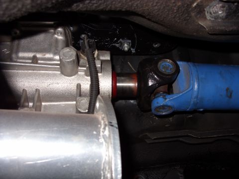 1978 Ford Mustang II - Underbody close-up of a driveshaft slip yoke and U-joint mated to the tail housing of a bare aluminum manual transmission, with the drivesh…