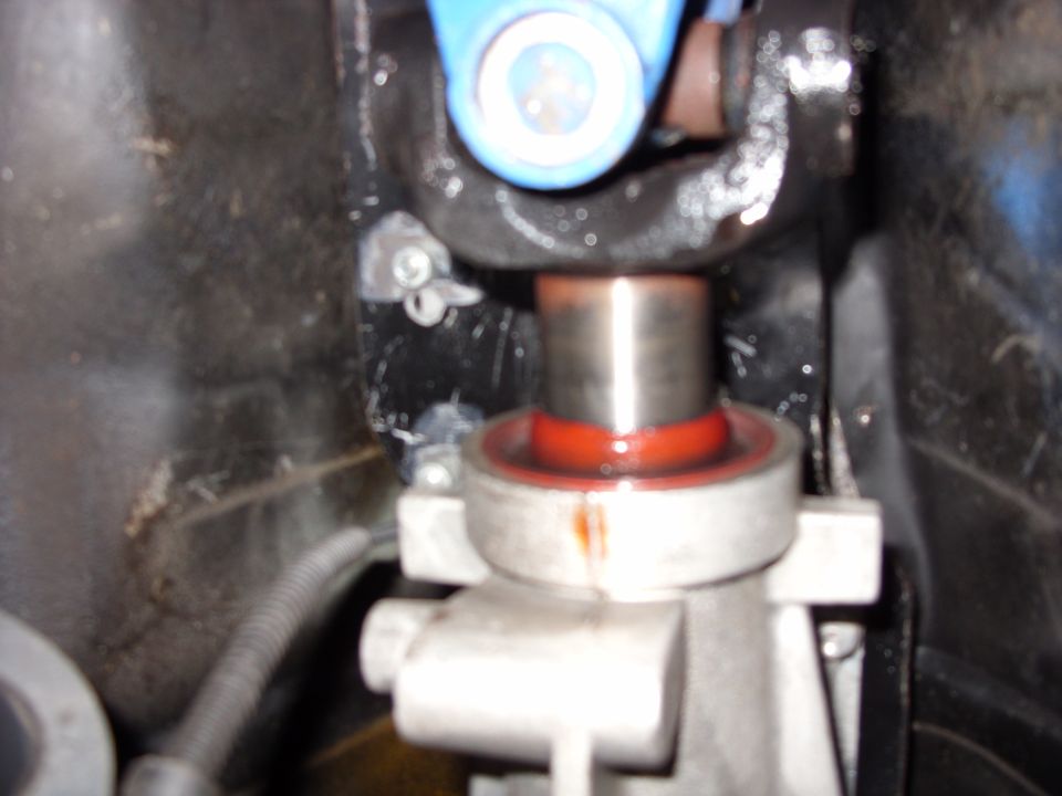 Close-up of steel shaft in bearing with red seal in aluminum housing under a car