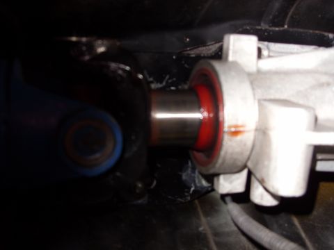 1978 Ford Mustang II - Tight close-up under a vehicle showing a driveshaft slip yoke, its polished chrome slip stub sliding into a red polyurethane-look seal at t…