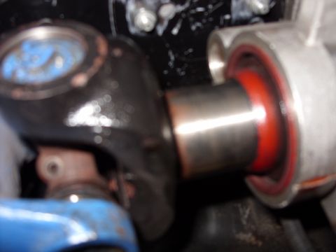 1978 Ford Mustang II - Tight close-up of a chrome-tipped shock or strut shaft passing through a red polyurethane bushing seated in a cast-aluminum housing, photog…