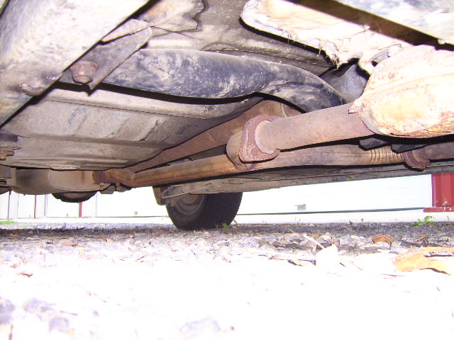 Underside of a vehicle showing rusted exhaust pipes and mufflers.