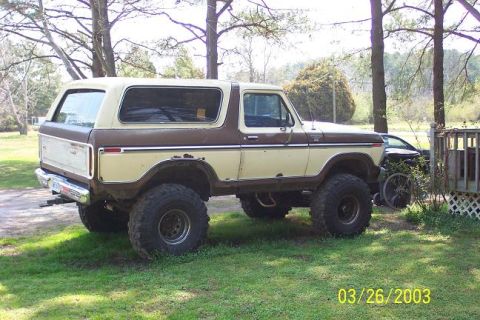 Lifted two-tone brown and cream Ford Bronco parked on grass