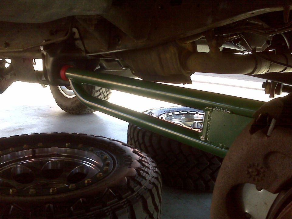 Underside of a vehicle with green suspension and off-road tires.