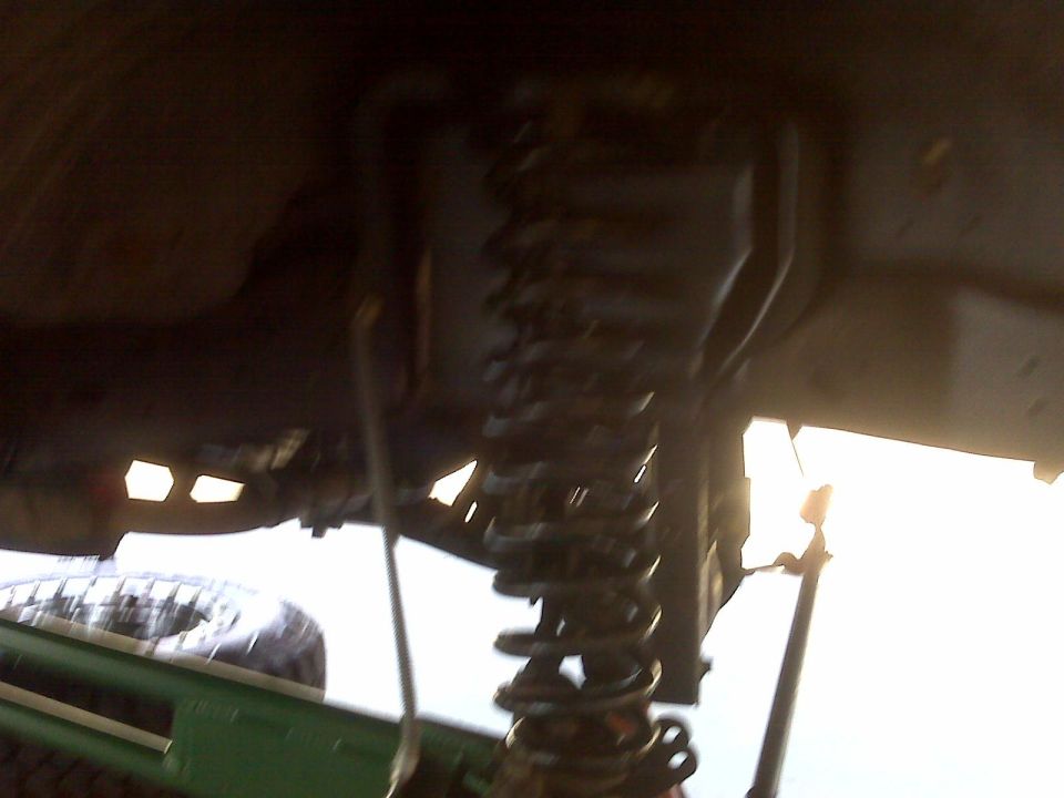 Underside of a vehicle showing suspension, coil spring, and tire.