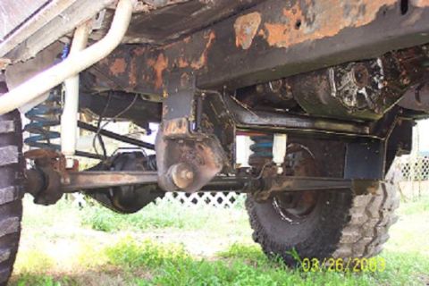 1979 Ford Bronco — Undercarriage view of a vehicle showing suspension, frame, and tires. Some rust is visible on the frame