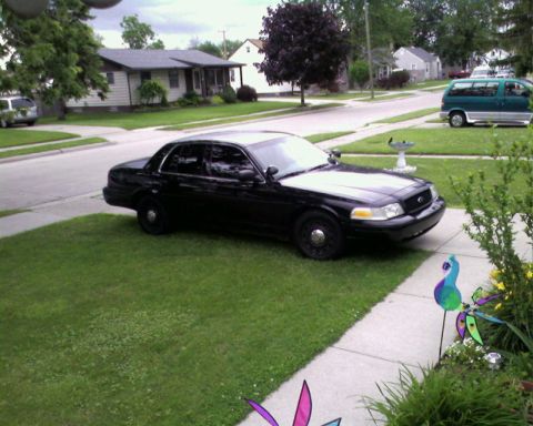 2004 Ford Crown Victoria - A black 2004 Ford Crown Victoria is parked on a residential lawn, viewed from a three-quarter front angle.