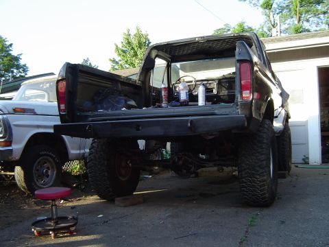 1979 Ford Bronco - A black Ford Bronco is parked next to a silver Ford truck, with its tailgate open and interior visible.