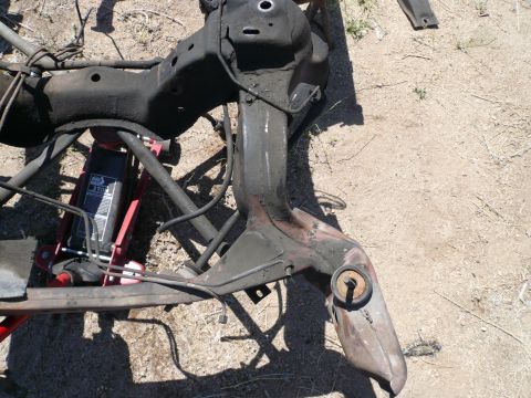1975 Ford Ranchero - Car subframe assembly on the ground, supported by a hydraulic jack. Part of a vehicle's chassis.