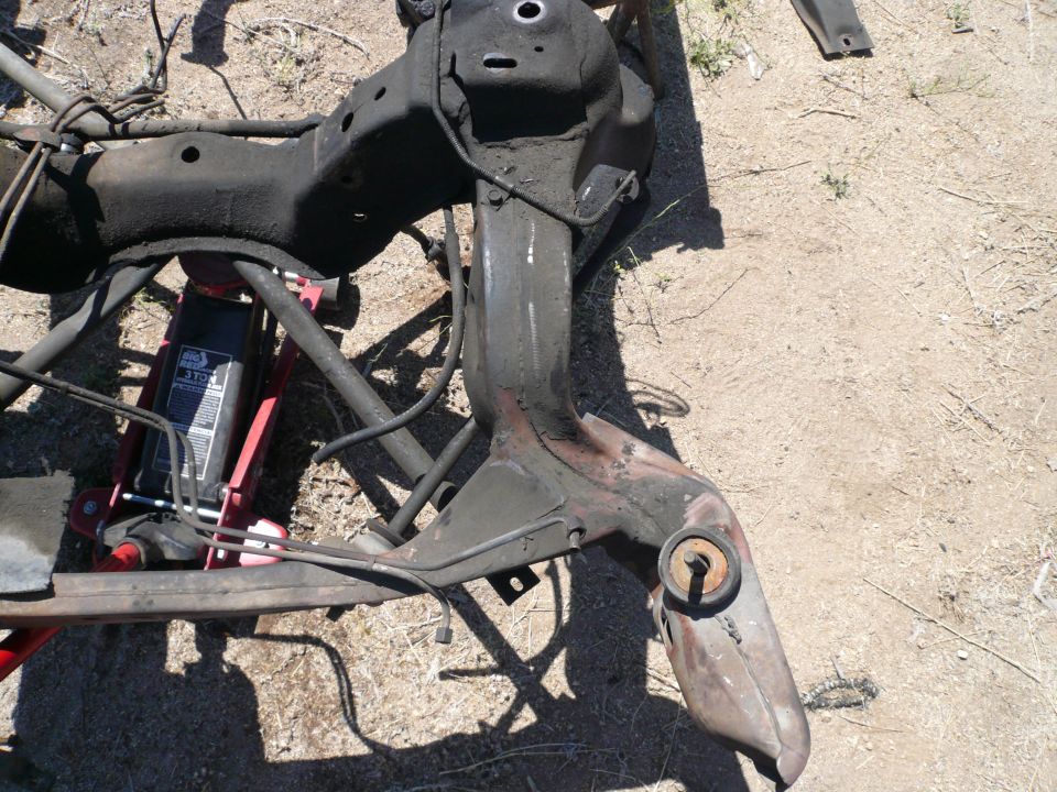 Car subframe assembly supported by a red hydraulic jack on the ground