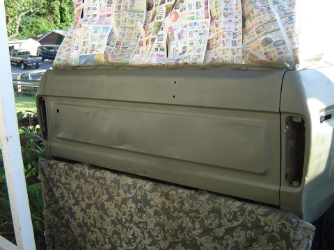 1978 Ford Bronco - Newspaper covers the rear of a vehicle undergoing painting, with other vehicles visible in the background.