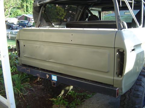 1978 Ford Bronco - The rear of an SUV is shown, with a custom bumper and visible roll cage. Other vehicles are parked in the background.