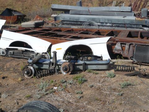 1975 Ford Ranchero - Junkyard scene with disassembled car parts including fenders and suspension components.