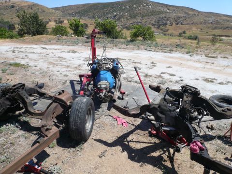 1975 Ford Ranchero - Vehicle chassis and engine are disassembled and laid out in a dry, outdoor area.