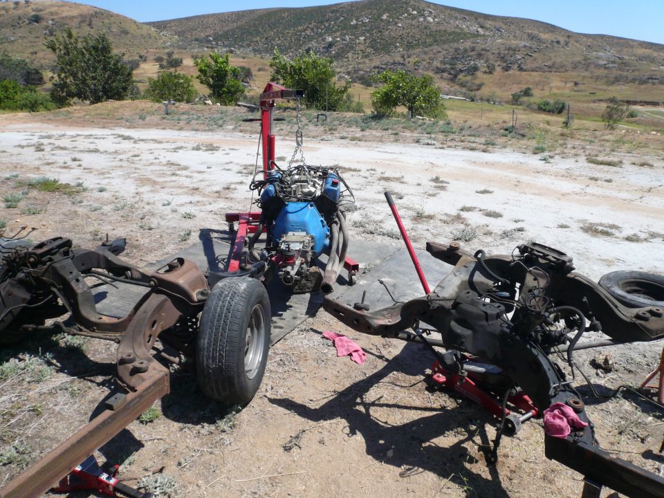 engine on stand, chassis frames, and a tire outdoors