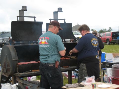 2000 Ford E350 - Two men are grilling food outdoors with a large smoker, and vehicles are visible in the background.