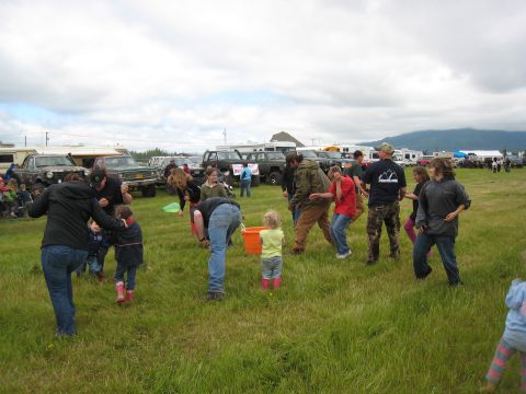 2000 Ford E350 - A group of people are interacting in a field with various vehicles present.