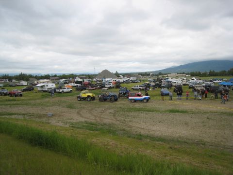 2000 Ford E350 - Outdoor event with numerous off-road vehicles, trucks, and trailers in a field.