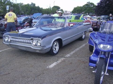 1970 Ford Ranchero - A two-tone convertible with a distinctive chrome grille is parked at an outdoor event.