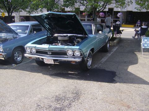 1970 Ford Ranchero - A light blue 1969 Chevrolet Chevelle SS coupe is parked with its hood open, revealing the engine bay.
