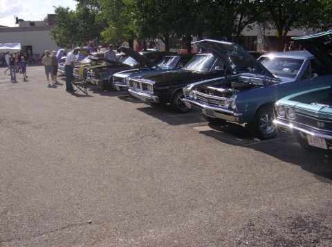 1970 Ford Ranchero - Several classic cars are lined up with their hoods open, displaying their engines at an outdoor event.