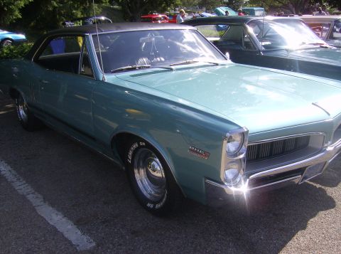 1970 Ford Ranchero - A teal 1967 Pontiac Firebird coupe is parked outdoors, with other vehicles visible in the background.