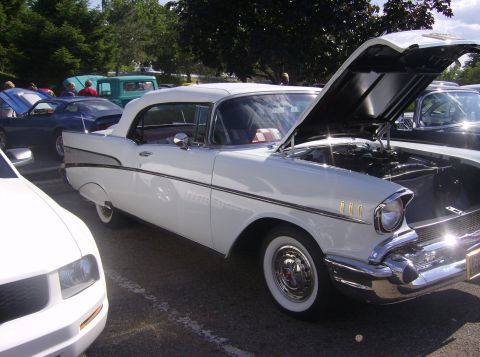 1970 Ford Ranchero - A white 1957 Chevrolet Bel Air is displayed with its hood open, alongside other vehicles at an outdoor event.