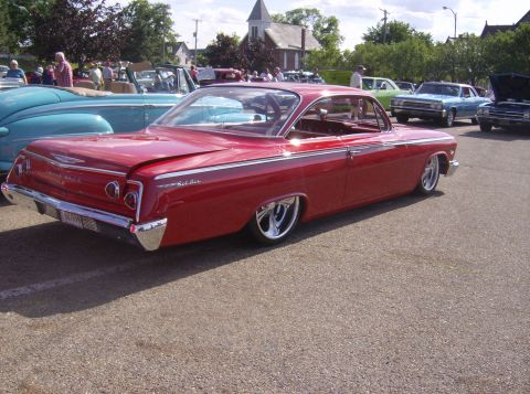 1970 Ford Ranchero - A red 1962 Chevrolet Bel Air is displayed at a car show with other vehicles in the background.