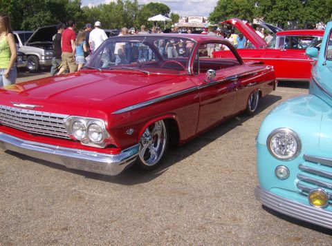 1970 Ford Ranchero - A classic red Chevrolet Impala is displayed at an outdoor car show with other vehicles.