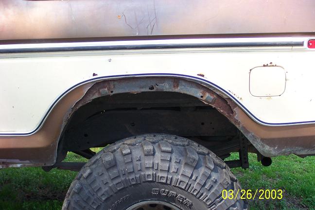 1979 Ford Bronco rear wheel well showing rust and a large off-road tire