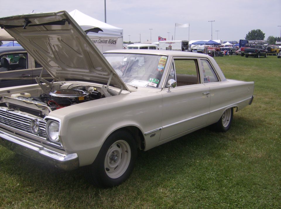 Classic light-colored sedan with hood open, parked on grass.