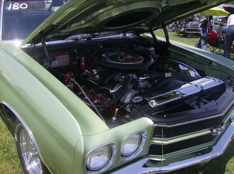 1970 Ford Ranchero - The front of a light green 1970 Ford Ranchero is visible with the hood open, revealing its V8 engine and chrome details.
