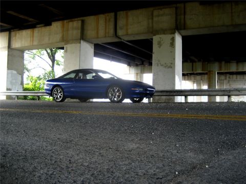 1993 Ford Probe - A blue Ford Probe is parked under a concrete overpass, viewed from a low angle on the asphalt road.