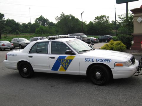 1991 Ford LTD Crown Victoria - white Ford Crown Victoria marked New Jersey State Police trooper car parked in a lot, shown from the passenger side with roof light bar.