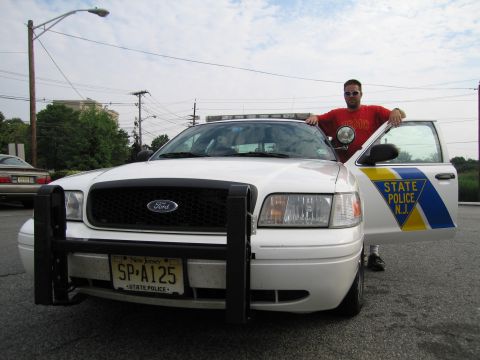 1991 Ford LTD Crown Victoria - white Ford Crown Victoria New Jersey State Police car with push bar and plate SP-A125, photographed front three-quarter with a man at the o…